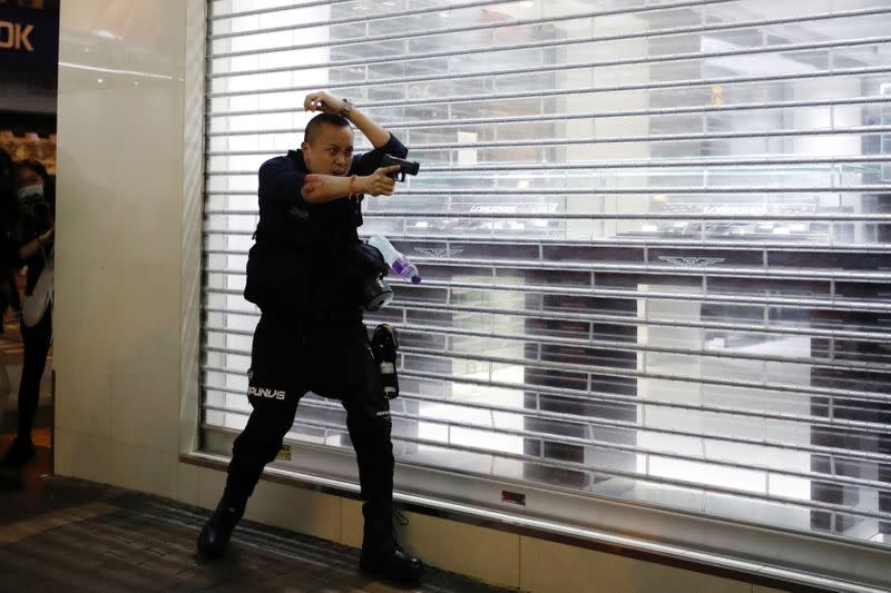 A police officer points his gun towards anti-extradition bill protesters after a clash, at Mong Kok, in Hong Kong