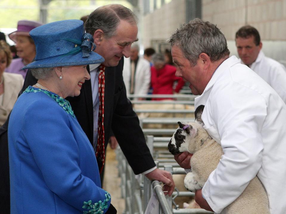 Queen Elizabeth speaks to a farmer holding a sheep