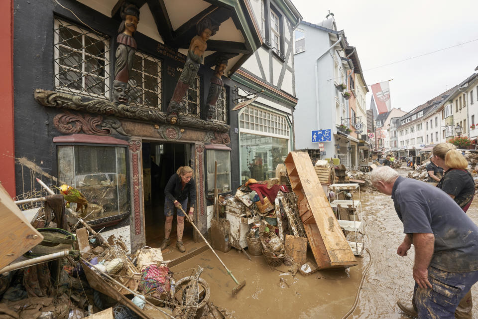 Residents and shopkeepers are trying to clear mud from their homes and move unusable furniture outside in Ahrweiler, western Germany, Saturday, July 17, 2021. Heavy rains caused mudslides and flooding in the western part of Germany. Multiple have died and are missing as severe flooding in Germany and Belgium turned streams and streets into raging, debris-filled torrents that swept away cars and toppled houses. (Thomas Frey/dpa via AP)