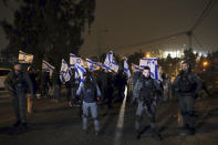 Israeli border police officers stand guard as Israeli right-wing demonstrators gather following a stabbing attack earlier in the day in the Sheikh Jarrah neighborhood in east Jerusalem, Wednesday, Dec. 8, 2021. An Israeli woman was stabbed and lightly wounded in the attack. The suspect, a Palestinian female minor, fled the scene and was later arrested inside a nearby school, police said. (AP Photo/Mahmoud Illean)