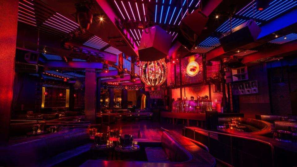 Nightclub with red light, tables, dance floor, and recessed seating.