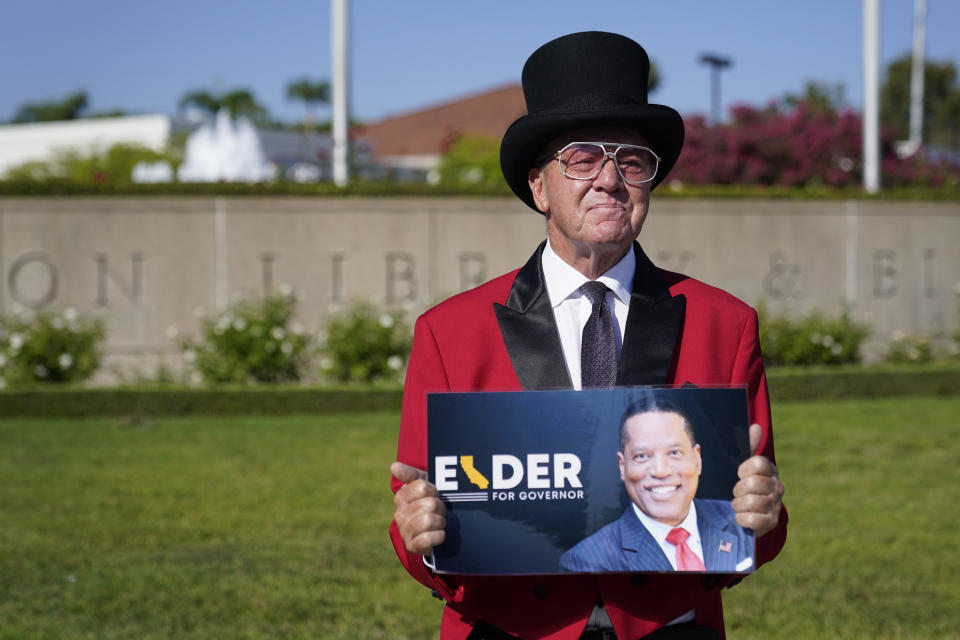 Gregg Donovan, a supporter of the California recall of Gov. Gavin Newsom and Republican candidate Larry Elder holds a sign outside of a debate by Republican gubernatorial candidates at the Richard Nixon Presidential Library Wednesday, Aug. 4, 2021, in Yorba Linda, Calif. Newsom faces a Sept. 14 recall election that could remove him from office. (AP Photo/Marcio Jose Sanchez)