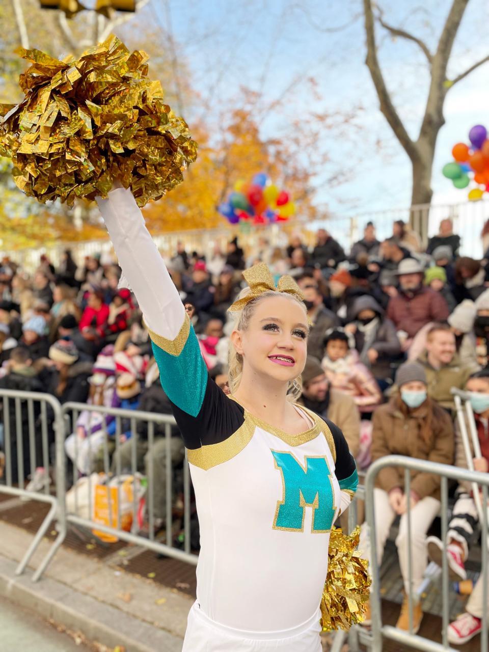Washington High School cheerleader Hallie Dancer waves to spectators along the route at the Macy’s Thanksgiving Day parade.
