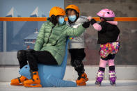 People wearing face masks to prevent the spread of the coronavirus skate at an outdoor ice skating rink in Beijing, Saturday, Jan. 23, 2021. (AP Photo/Mark Schiefelbein)