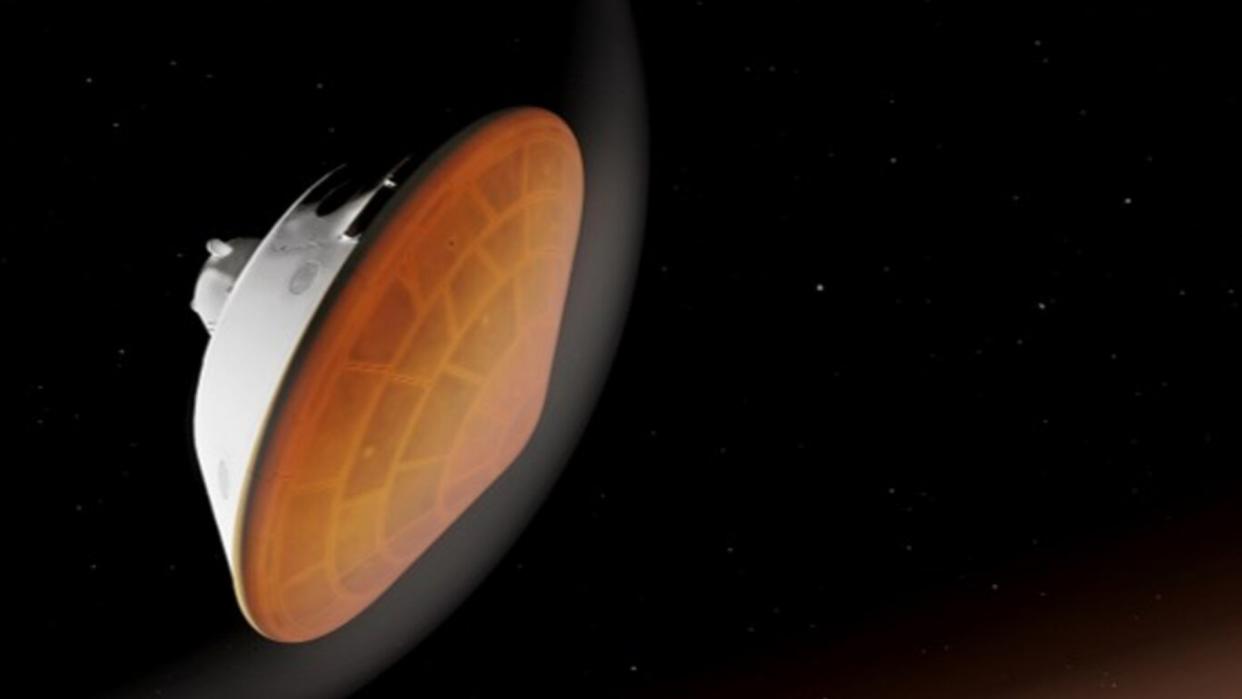  A cone-shaped spacecraft with a rounded bottom entering a planet's atmosphere surrounded by glowing gas. 