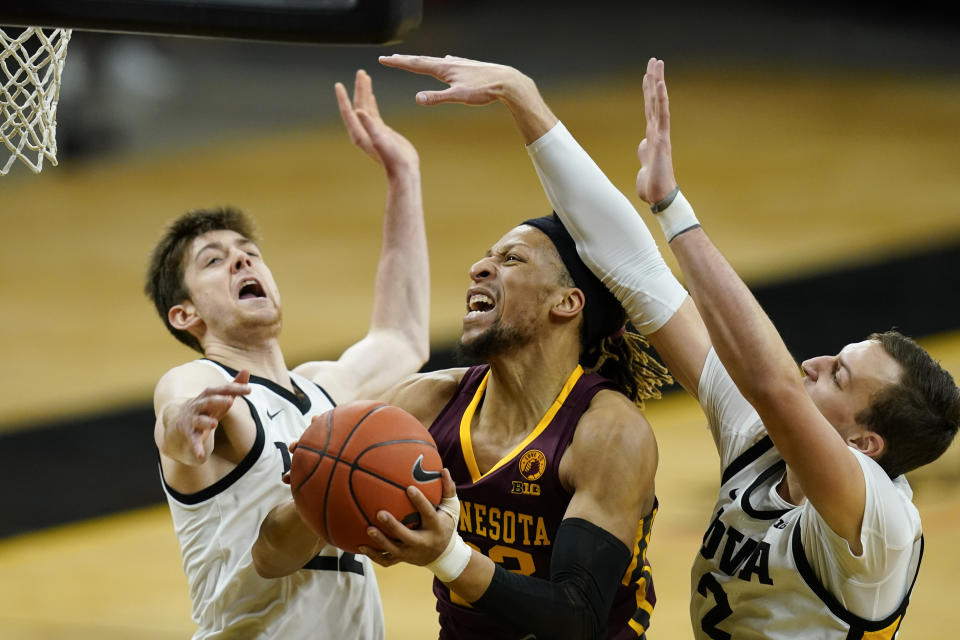 Minnesota forward Brandon Johnson, center, drives to the basket between Iowa forward Patrick McCaffery, left, and forward Jack Nunge, right, during the first half of an NCAA college basketball game, Sunday, Jan. 10, 2021, in Iowa City, Iowa. (AP Photo/Charlie Neibergall)