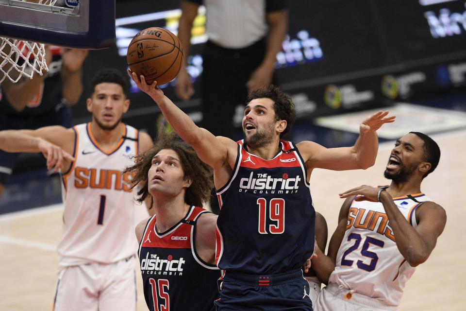 Washington Wizards guard Raul Neto (19) goes to the basket past Phoenix Suns forward Mikal Bridges (25) and guard Devin Booker (1) during the second half of an NBA basketball game, Monday, Jan. 11, 2021, in Washington. Wizards center Robin Lopez (15) looks on. (AP Photo/Nick Wass)