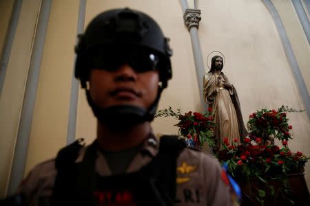 A policeman walks near a statue of Jesus Christ as he clears the area inside Jakarta Cathedral ahead of Christmas celebrations in Indonesia, December 24, 2016. REUTERS/Beawiharta