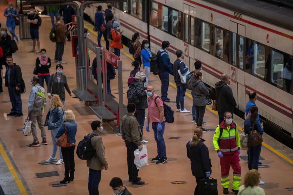 Commuters wearing face masks to protect against coronavirus stand on the platform at Atocha train station in Madrid.  (ASSOCIATED PRESS)