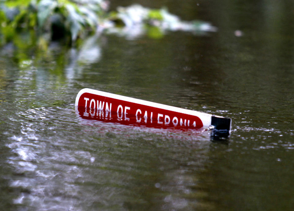 Floodwaters bisect a row of type on a sign for a home saying: Town of Caledonia.