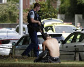 A man rests on the ground as he speaks on his mobile phone across the road from mosque in central Christchurch, New Zealand, Friday, March 15, 2019. A witness says a number of people have been killed in a mass shooting at a mosque in the New Zealand city of Christchurch; police urge people to stay indoors. (AP Photo/Mark Baker)