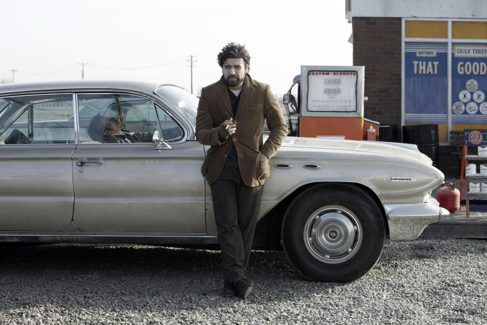 Oscar Isaac stands up against a car that Garrett Hedlund is in