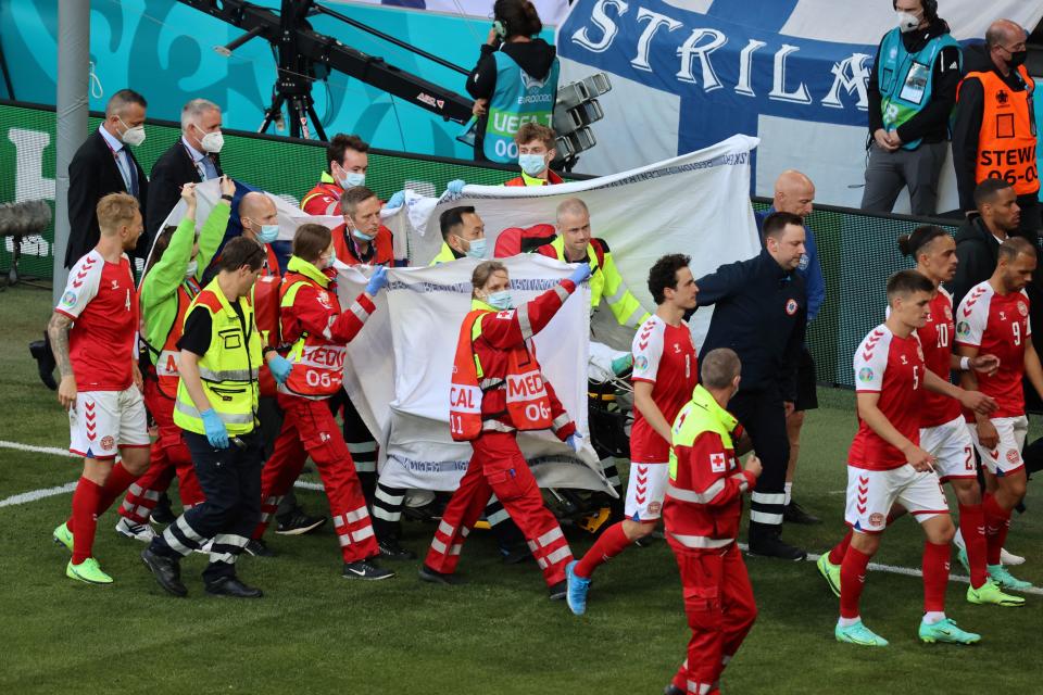 Players escort paramedics as Denmark's midfielder Christian Eriksen is evacuated from the pitch during the EURO 2020 in June. The medics and Danish captain Simon Kjær are being honored by UEFA with the President's Award. (Photo by WOLFGANG RATTAY/POOL/AFP via Getty Images)