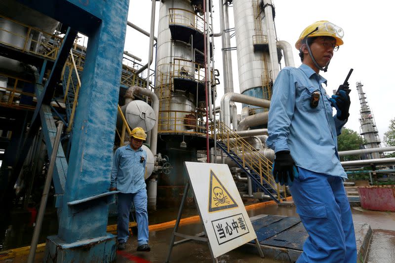 FILE PHOTO: Technicians walk down the refinery which produces ethanol gasoline for vehicles, at China's Petroleum and Chemical Corporation, or Sinopec, Tianjin company in Tianjin