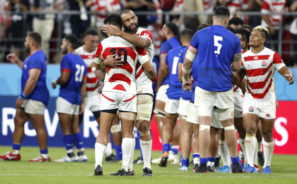 Japan's Michael Leitch embraces teammate Japan's Yu Tamura after their Rugby World Cup Pool A game at City of Toyota Stadium against Samoa in Tokyo City, Japan, Saturday, Oct. 5, 2019. Japan defeated Samoa 38-19.(AP Photo/Shuji Kajiyama)