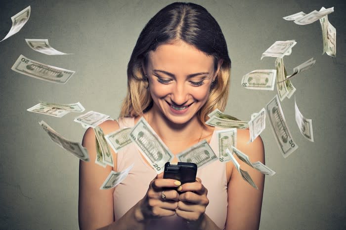 Woman playing on cell phone and money flying out of it