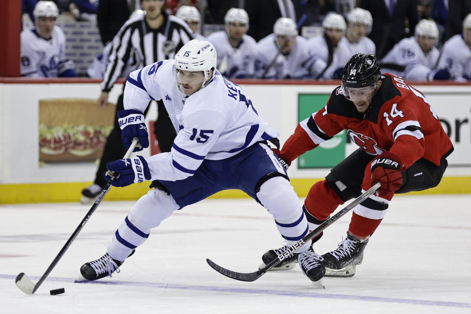 Toronto Maple Leafs center Alexander Kerfoot (15) keeps the puck from New Jersey Devils right wing Nathan Bastian during the first period of an NHL hockey game Wednesday, Nov. 23, 2022, in Newark, N.J. (AP Photo/Adam Hunger)