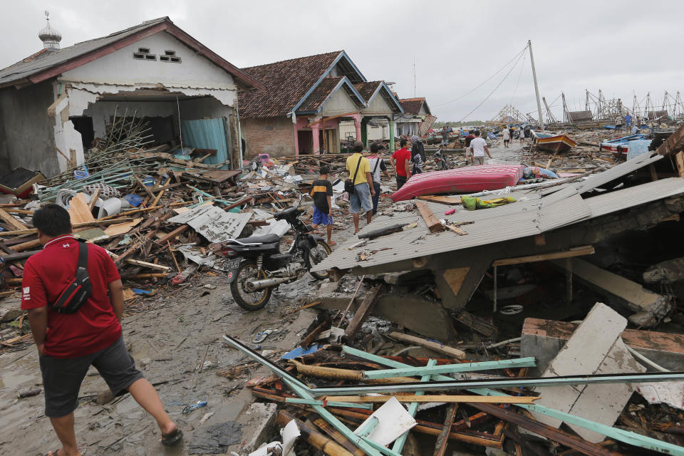 People inspect the damage at a tsunami-ravaged village in Sumur, Indonesia, Tuesday, Dec. 25, 2018. The Christmas holiday was somber with prayers for tsunami victims in the Indonesian region hit by waves that struck without warning Saturday night.(AP Photo/Tatan Syuflana)