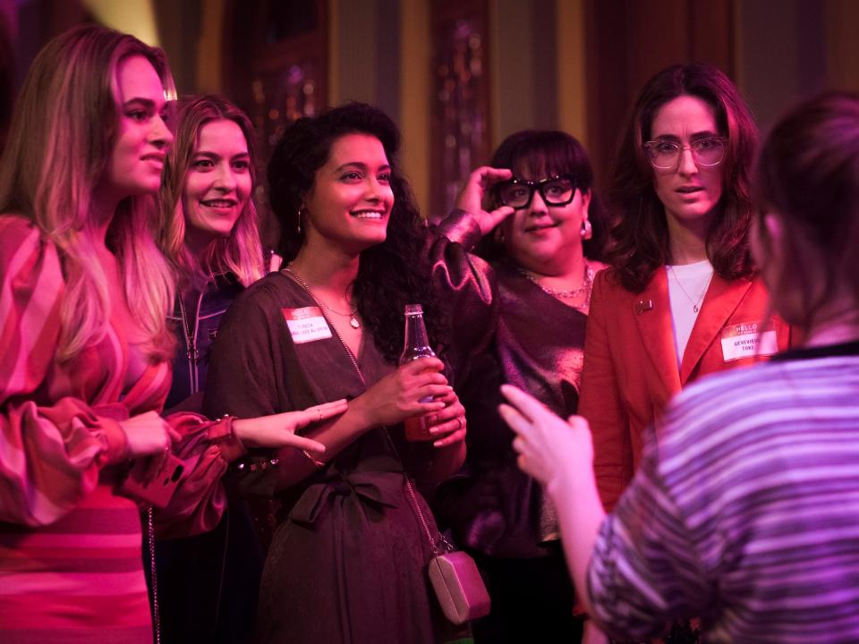 a group of women at a party with pink lighting, gathered together in class of 07