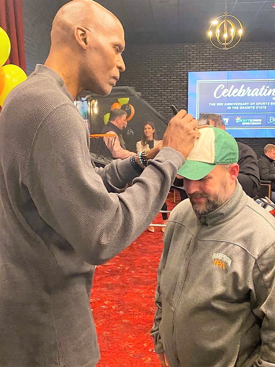 Boston Celtics legend and NBA Hall of Famer Robert Parish signs TJ Rowe's hat Thursday, March 30, 2023 at The Brook in Seabrook. Rowe, a Seacoast basketball official for the past 30 years, also has autographs by other former Celtics, such as KC Jones, Tommy Heinsohn and Cedric Maxwell, on the same hat.