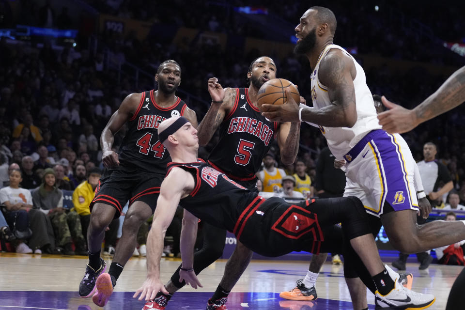 Chicago Bulls guard Alex Caruso, left, draws a charge on Los Angeles Lakers forward LeBron James during the second half of an NBA basketball game, Sunday, March 26, 2023, in Los Angeles. (AP Photo/Marcio Jose Sanchez)