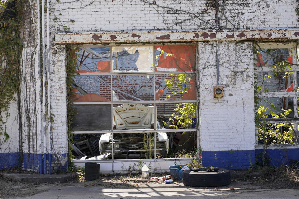 A rusting vehicle sits in one of the open service bays at a vacant garage in downtown Itta Bena, Miss., Thursday, Oct. 22, 2020. Area residents believe the high price of electricity provided by the city as one of the reasons for store closures. (AP Photo/Rogelio V. Solis)