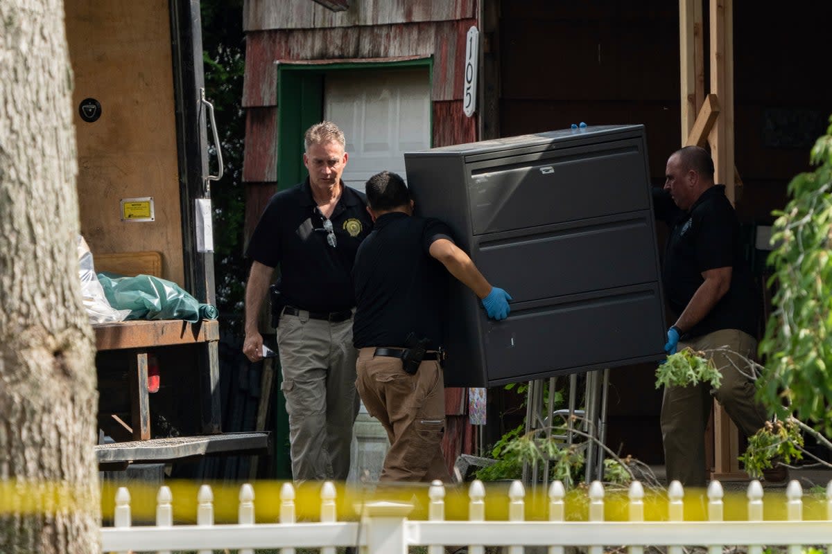 New York State police officers move a metal cabinet as law enforcement searches the home of Rex Heuermann, Saturday, July 15, 2023, in Massapequa Park, N.Y. (AP)