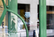 Cafe employee, Djibril, cleans the window of a closed cafe as they prepare to reopen, in Paris, Monday, June 1, 2020. Local Parisians are savoring their cafe au lait and croissants at the Left Bank's famed Cafe de Flore, or on the cobbled streets of the ancient Le Marais for the first time in almost three months. As virus confinement measures were relaxed Tuesday, cafes around France were allowed to reopen.(AP Photo/Thibault Camus)