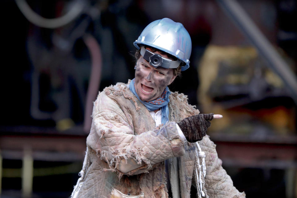 In this Saturday, May 18, 2019, photo actor Tami Dixon, wearing an industrial hardhat while portraying "The Fool" character, performs in the Quantum Theatre production of Shakespeare's "King Lear" at the site of the old Carrie steel producing blast furnace in Swissvale, Pa. Karla Boos, the artistic director said using this backdrop gives a sense of the enormity of the steel industry and the enormity of its collapse and those are wonderful metaphors for the play. (AP Photo/Keith Srakocic)
