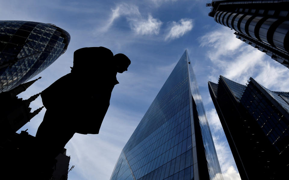 A man walks past The Gherkin and other office buildings in the City of London