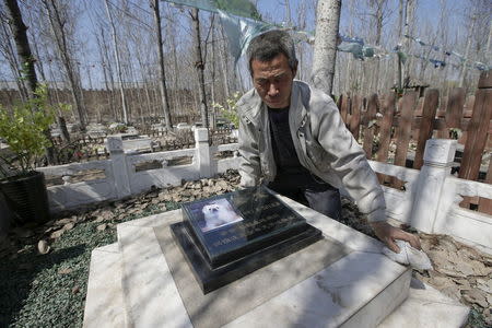 Baifu pet cemetery worker Zhang Youwang cleans the tomb of pet dog Baobao, which died at the age of 13, during his daily work ahead of the Qingming Festival on the outskirts of Beijing China, March 26, 2016. REUTERS/Jason Lee