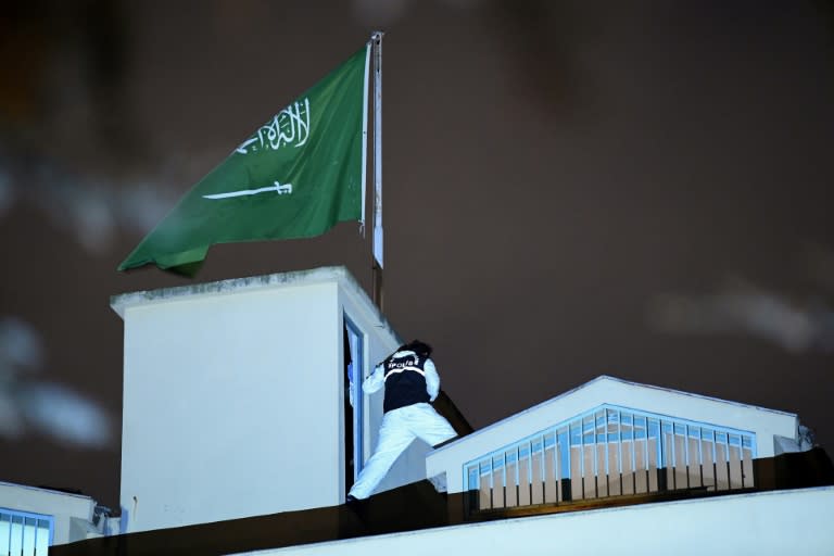 A Turkish forensic expert stands next to the Saudi flag on the roof of the consulate in Istanbul on October 15, 2018 during a much anticipated eight-hour search in the investigation into missing Saudi journalist Jamal Khashoggi