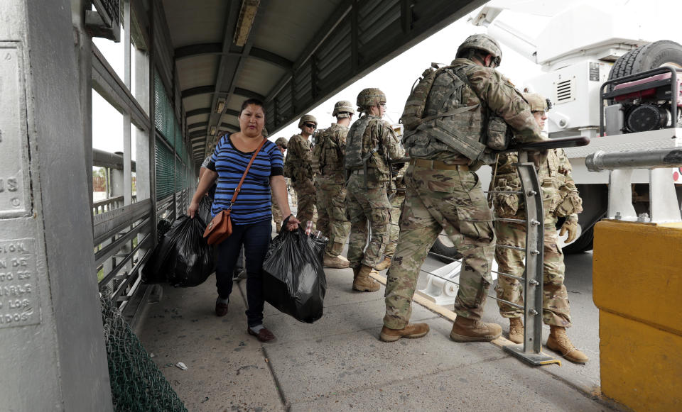 Pedestrians pass members of the U.S. military working to place razor wire along the U.S.-Mexico border on the McAllen-Hidalgo International Bridge, Friday, Nov. 2, 2018, in McAllen, Texas. (AP Photo/Eric Gay)