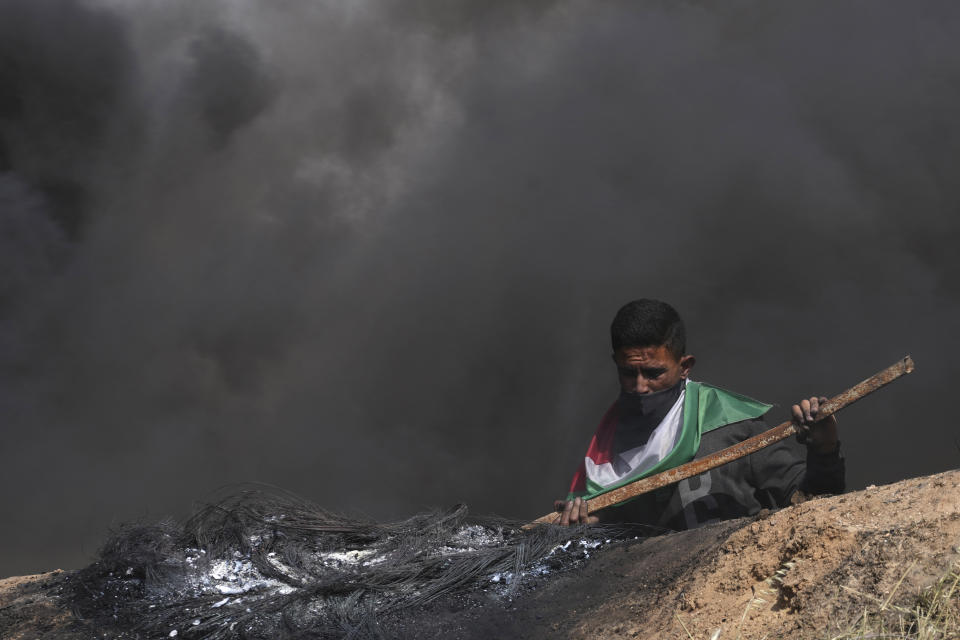 A Palestinians burns tires during a protest against an Israeli police raid of the Al-Aqsa Mosque compound in Jerusalem's Old City early Wednesday, along the border fence with Israel, east of Gaza City, Wednesday, April 5, 2023. (AP Photo/Adel Hana)