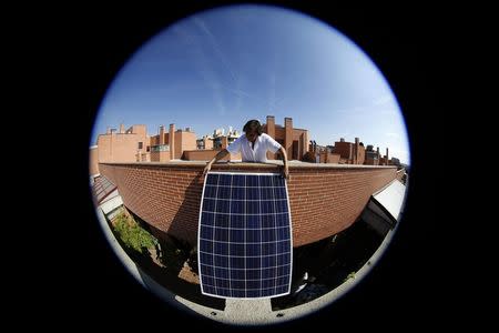 Spanish architect Inaki Alonso install a solar panel on a beam over his central Madrid roof terrace September 9, 2014. REUTERS/Sergio Perez