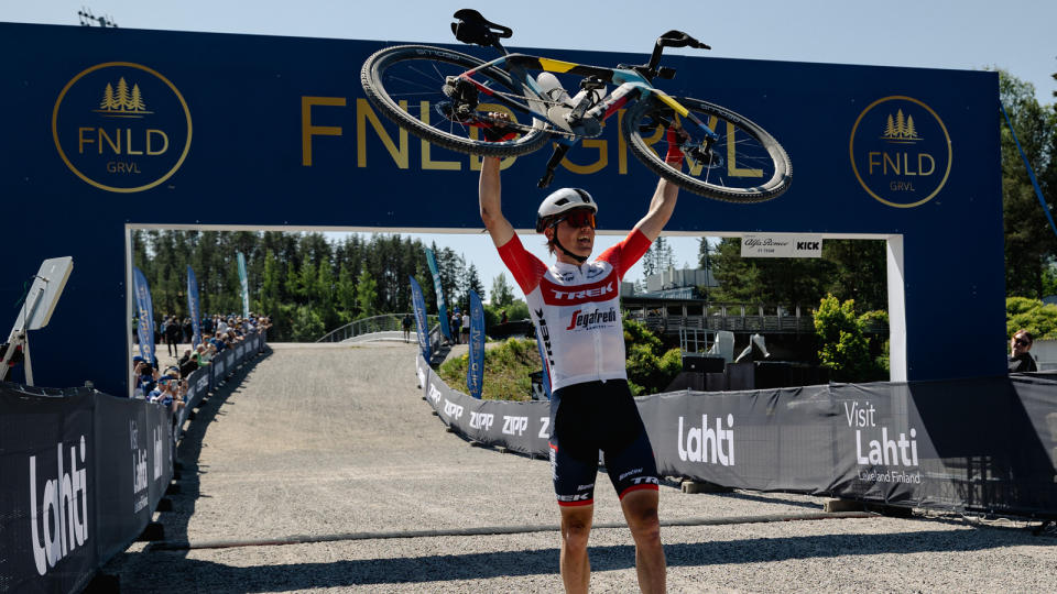 Toms Skujins (Trek-Segafredo) holds his bike above his head at the finish line