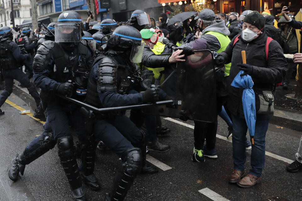 Riot police officers scuffle with demonstrators during a protest, Saturday, Dec.12, 2020 in Paris. Protests are planned in France against a proposed bill that could make it more difficult for witnesses to film police officers. (AP Photo/Lewis Joly)