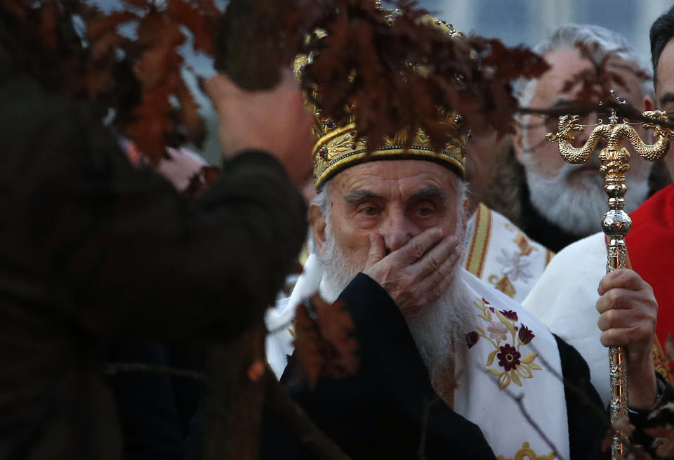 FILE - In this Jan. 6, 2020. file photo, Serbian Patriarch Irinej gestures during a ceremonial burning of dried oak branches, in front of St. Sava church in Belgrade, Serbia. The Serbian Orthodox Church says Patriarch Irinej has been hospitalized after testing positive for the new coronavirus. Patriarch Irinej last Sunday led the prayers at the big public funeral for the church head in Montenegro, Bishop Amfilohije, who had died after contracting the virus. (AP Photo/Darko Vojinovic, File)