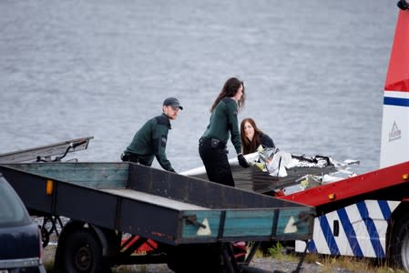 Emergency personnel unload parts of wreckage retrieved from the crash site at Ume river outside Umea