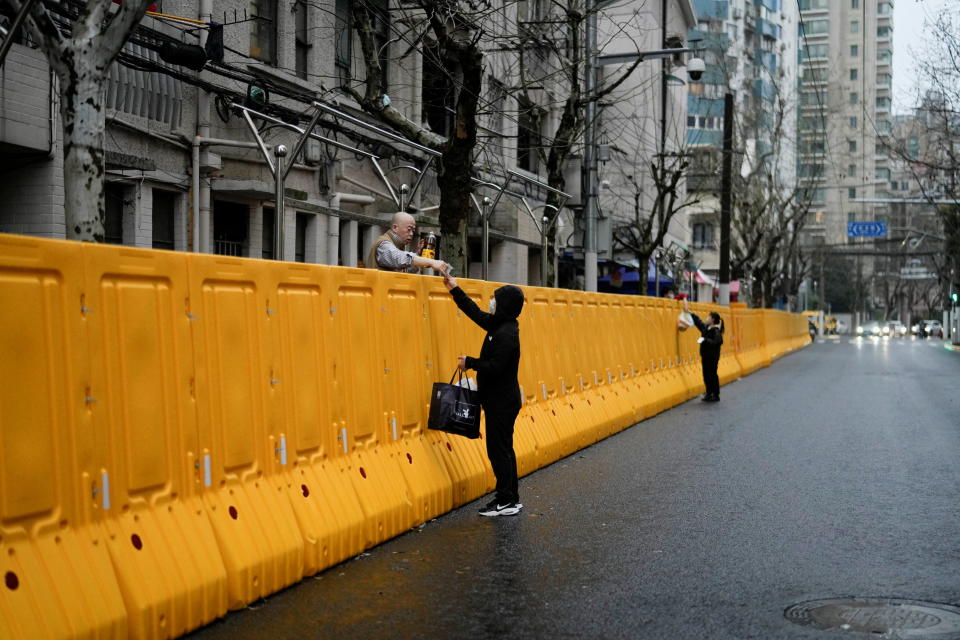 People pass food to residents over the barriers of an area under lockdown, amid the coronavirus disease (COVID-19) pandemic, in Shanghai, China March 25, 2022. REUTERS/Aly Song