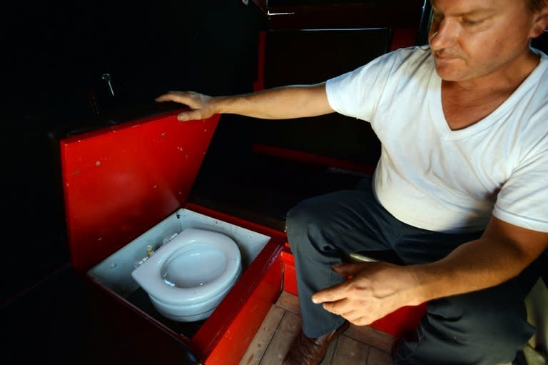 Greg Kloehn shows off the toilet in the home he made from a trash dumpster August 15, 2013 in New York. There's no room to swing a cat in the tiny home, so the gas barbecue and shower are welded onto the outside