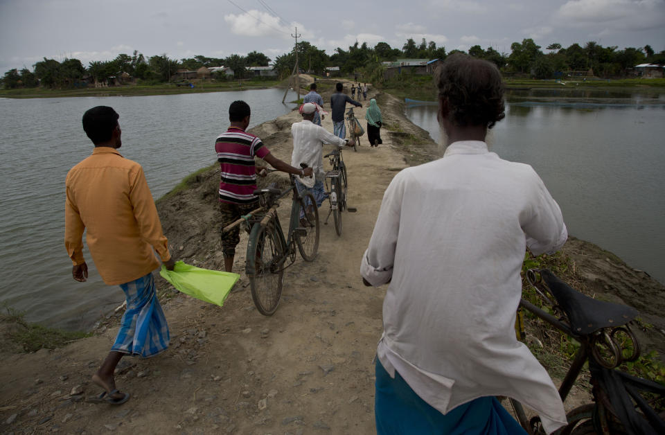Villagers walk on an embankment on their way to check names in the final list of the National Register of Citizens (NRC) at an NRC center in Pabhokati village in Morigaon district, in the northeastern Indian state of Assam, Saturday, Aug. 31, 2019. India has published the final citizenship list in the Indian state of Assam, excluding nearly two million people amid fears they could be rendered stateless. The list, known as the National Register of Citizens (NRC), intends to identify legal residents and weed out illegal immigrants from the state. (AP Photo/Anupam Nath)