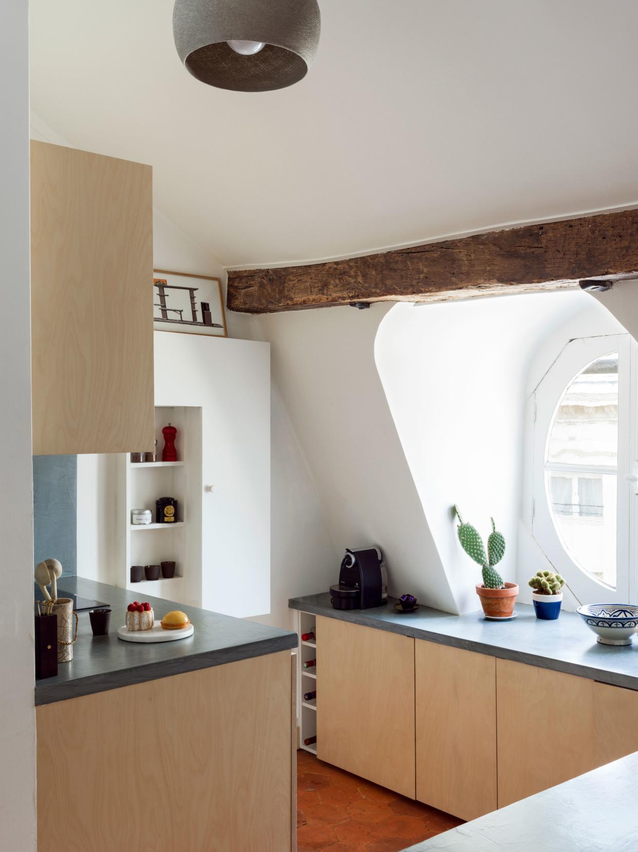 The original wooden beams, terra-cotta floors, and oval-shaped windows were restored to retain the kitchen’s historic Parisian charm.