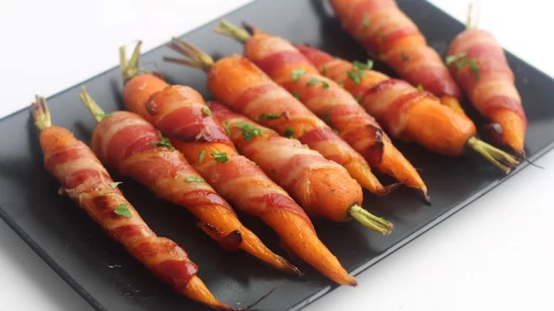 Bacon wrapped carrots on black plate