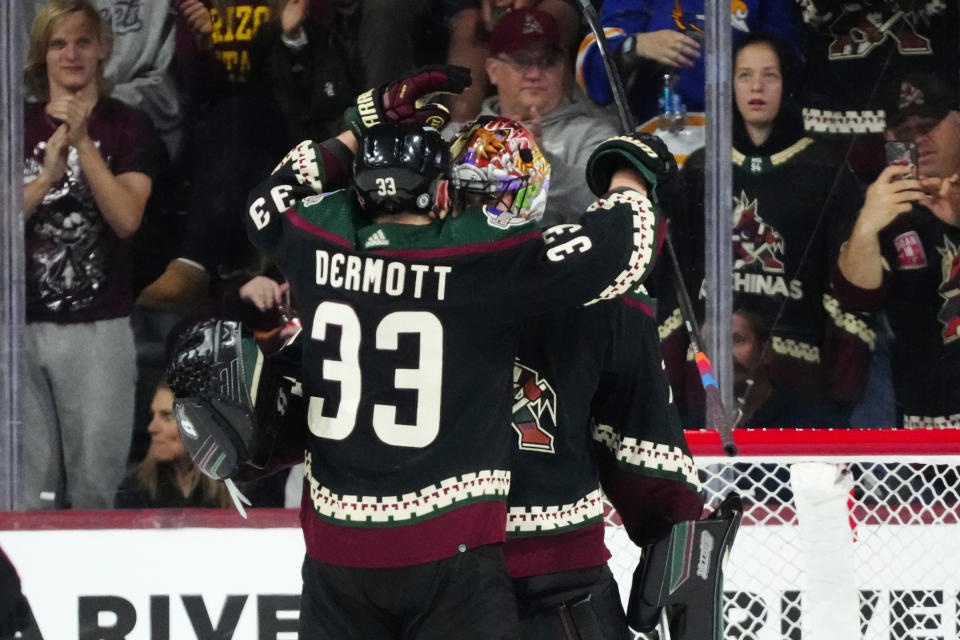 Arizona Coyotes defenseman Travis Dermott (33) celebrates with goaltender Karel Vejmelka, right, as time expires in the team's NHL hockey game against the Columbus Blue Jackets, Tuesday, March 26, 2024, in Tempe, Ariz. The Coyotes won 6-2. (AP Photo/Ross D. Franklin)