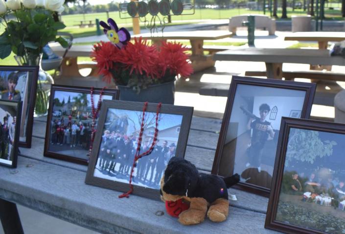 Photos, flowers and other objects in remembrance of Dylan Dooling sit on a picnic table at Curt Andre Park in Turlock on June 8 prior to a candlelight vigil.