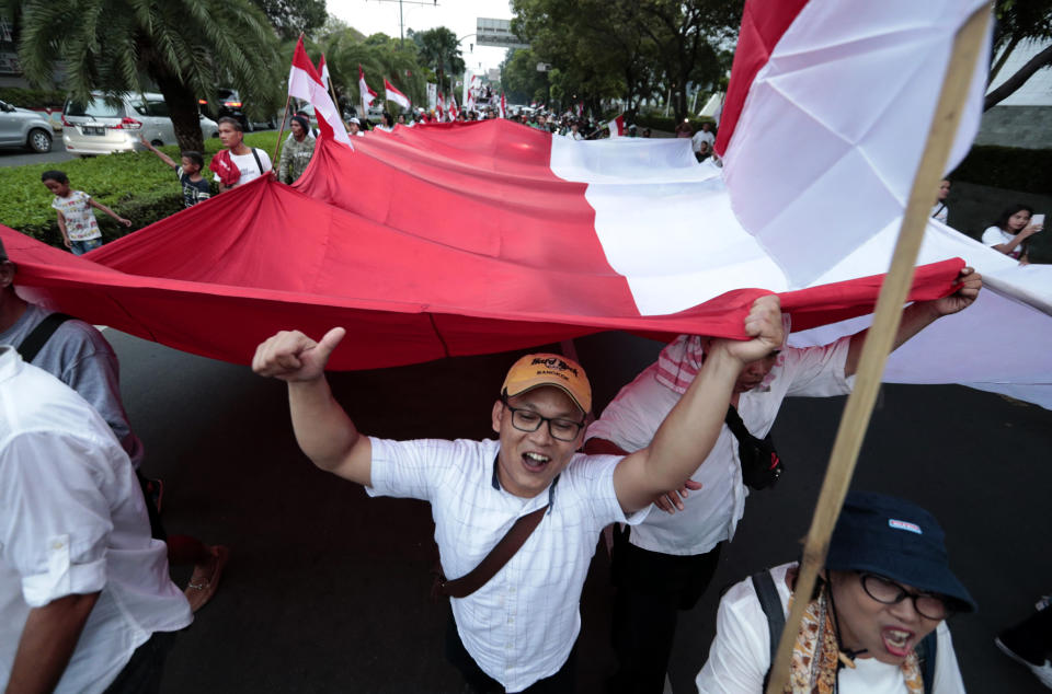 Supporters of Indonesian President Joko Widodo hold a large national Red-White flag as they celebrate during a rally in Jakarta, Indonesia, Wednesday, April 17, 2019. Widodo is on track to win a second term, preliminary election results showed Wednesday, in apparent victory for moderation over the ultra-nationalistic rhetoric of his rival Prabowo Subianto. (AP Photo/Dita Alangkara)