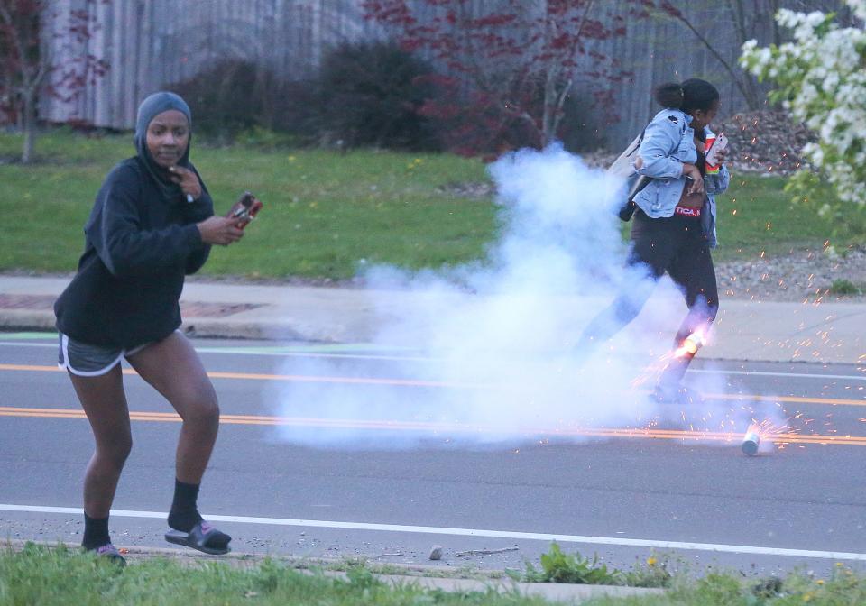 Two women run when a tear gas cannister is deployed near them during an April 19 protest on Copley Road in Akron.