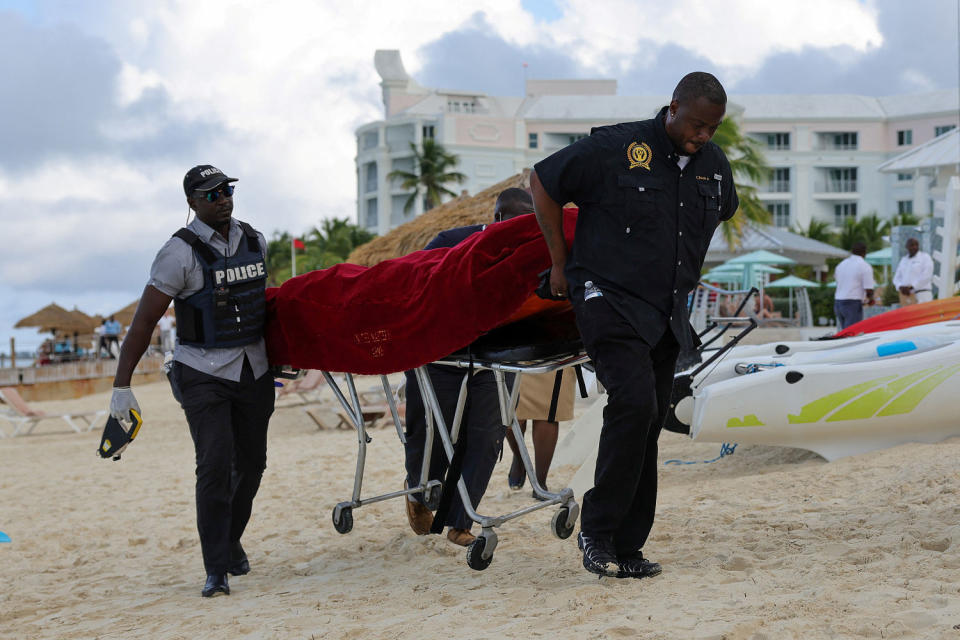 The covered body of a tourist is carried away on a stretcher. following fatal shark attack (Dante Carrer / Reuters)