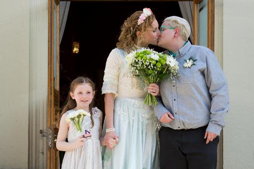 Nikki Pettit (C) y Tanya Ward (d) se besan mientras posan para una fotografía junto a la dama de honor Mae (i) luego de su boda en Brighton, en el sur de Inglaterra, el 29 de marzo de 2014 (AFP | Leon Neal)